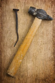 hammer with a rusty nail against a wooden board