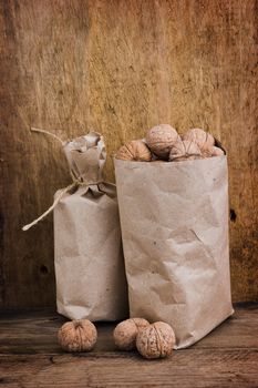 Walnuts in paper bags on the background of an old wooden board