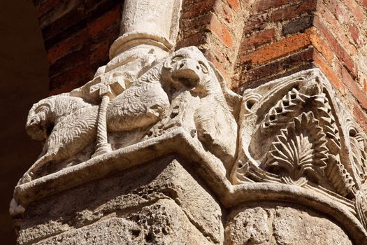 Detail of the external arcade of the Church of Saint Ambrose (Sant'Ambrogio) of Milan. Capitol with abstract and zoological figures in white stone.