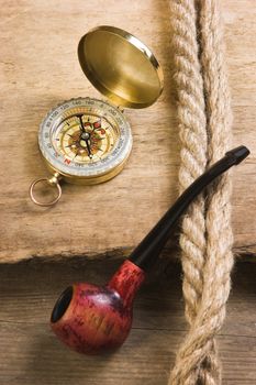 Compass and a pipe with a rope on the background of the old board