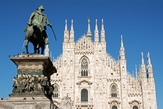 Gothic facade of Milan Cathedral in Piazza del Duomo. It is the fourth largest church in the world. The construction started in 1386 and took about five centuries. On the left the monument to king Vittorio Emanuele II.