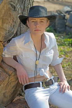 Portrait of a woman in a white shirt and cowboy hat on a ranch.