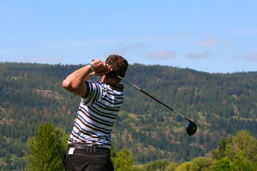 Young golfer following his ball after teeing off