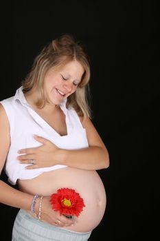 Heavily pregnant blond female against a black background