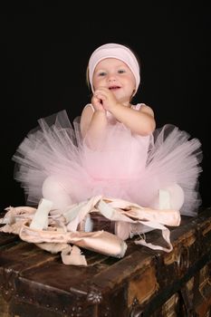 Baby ballerina sitting on an antique trunk