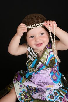 Beautiful little blond girl playing with a string of pearls