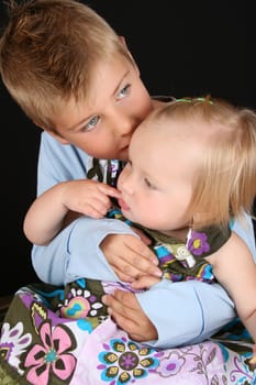 Cute brother holding his toddler sister in his arms 