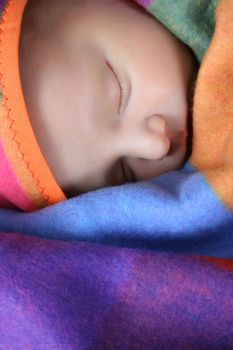 Beautiful newborn boy wrapped in a colorful blanket