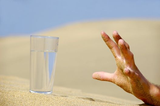 Hand is reaching for a fresh glass of cold water in desert.