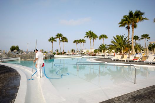 A man is cleaning the pool at a nice hotel resort.