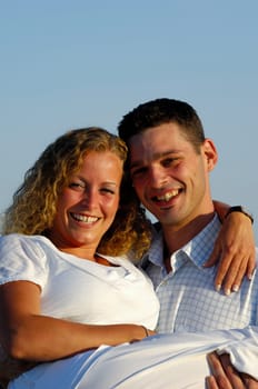 A sweet young couple is posing in the sun.