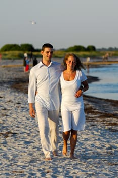 A young happy couple is walking on a beach.