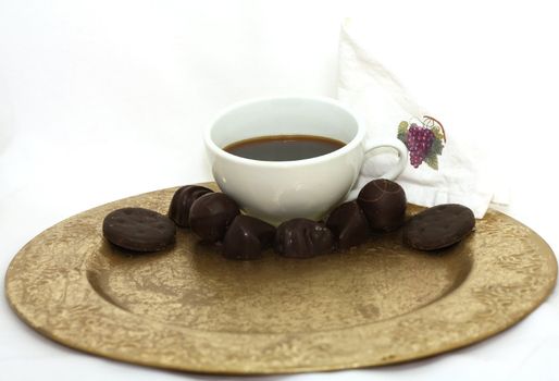 Cup of coffee with chocolate candy on white.
