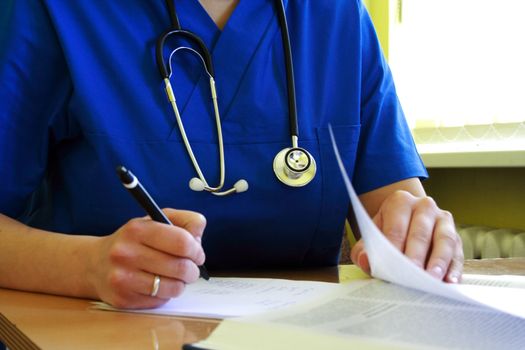 medical doctor with stethoscope is writing patient history