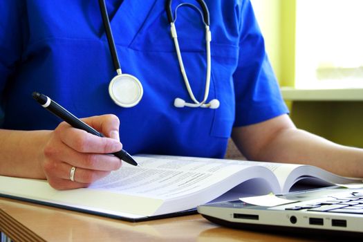 medical doctor with stethoscope is writing patient history