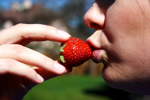 face of the beautiful woman eating a strawberry