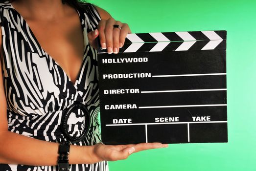 woman holding a movie clapper set against a chroma green screen