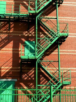 red brick wall with green metal stairs