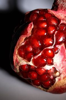 Fragment of a ripe pomegranate on a grey background