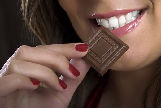 A beautiful woman satisfying a chocolate candy