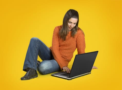 Beautiful student woman with a laptop over a yellow background