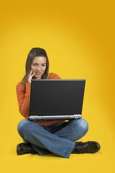 Beautiful student woman with a laptop over a yellow background