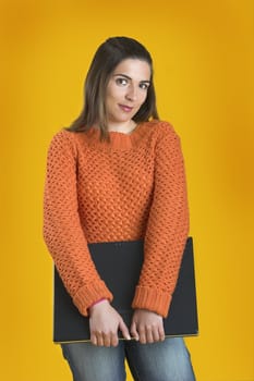 Beautiful student woman with a laptop over a yellow background