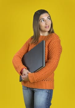 Beautiful student woman with a laptop over a yellow background