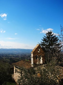A view of an old church bell tower and the Umbrian countryside in Assisi, Italy.