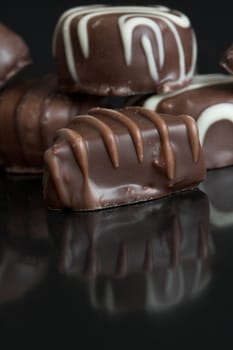 Delicious chocolates on black background with reflection