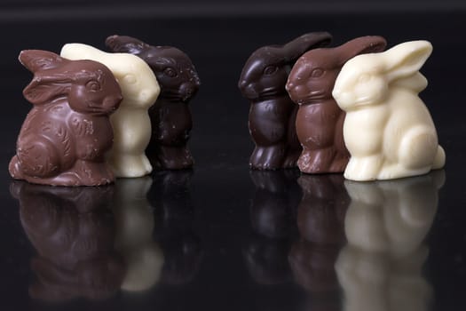 Delicious chocolate easter bunnies in a row on black background with reflection