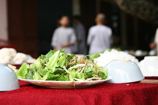 Fresh green salad served on a table with people in the background