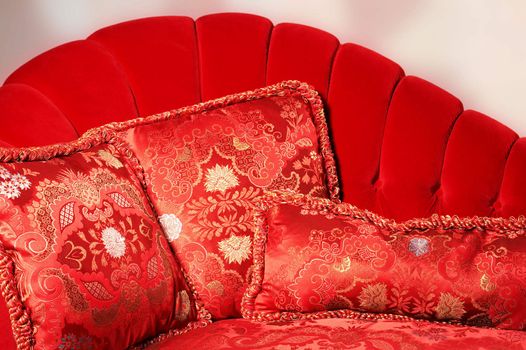 Three pillows with an ornament on a red sofa