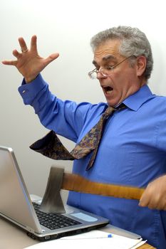 An older businessman fed up with his laptop, takes an axe to it.