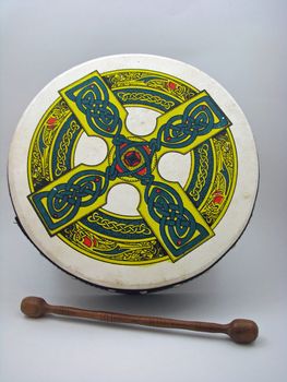 An Irish bodhran (drum) with a celtic design and wooden tipper.