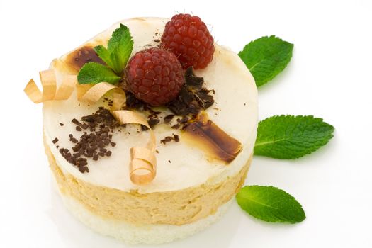 Close-up of a pear mousse cake decorated with raspberries and mint leaves