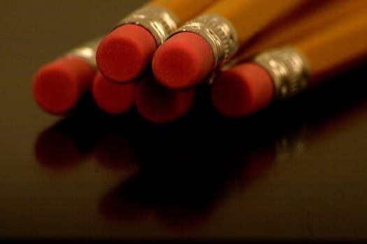 Erasers on Wood Pencils with depth of field and reflections on a table.
