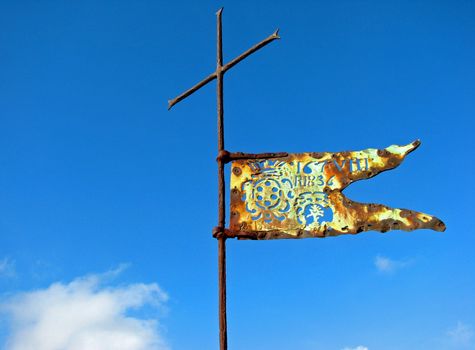 A Renaissance flag and cross atop a Tuscan castle and fortress.