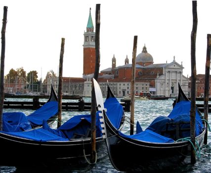 A close up view of gondolas in the Venice lagoon. San Giorgio Maggiore Church is in the distance.