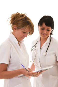 Two young nurses standing next to eachother discussing their patients