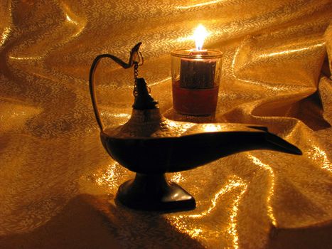An India Aladdin's Lamp on a dark gold background with candlelight.