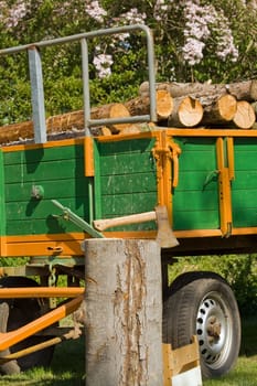 A trailer load with wood, before it an axe in log