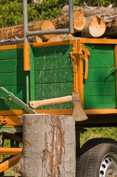 A trailer load with wood, before it an axe in log