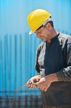 Authentic construction worker cutting reinforcement binding wire with a pair of pliers