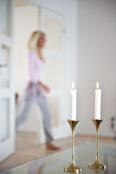 Woman passes through the living room which is illuminated by candle ligts.