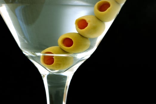 A macro shot of a martini with extra olives.