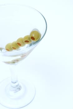 A macro shot of a martini with extra olives.