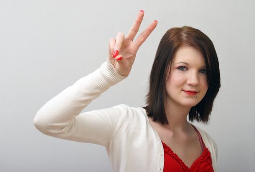 A young girl is giving the peace sign.