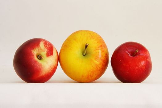 three pieces of fresh fruit apple nectarine and plum