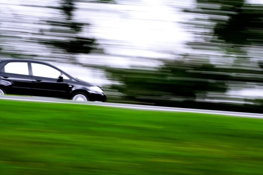a black car rushing away on a countryside highway